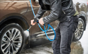 Professional demonstrating pre-cleaning inspection and preparation steps for pressure washer car cleaning